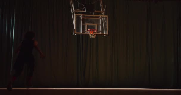 Ung kaukasisk lockigt hår basketspelare spelar kasta bollen i korgen kväll sport hall parkett droppande balk ljus slam dunk — Stockvideo