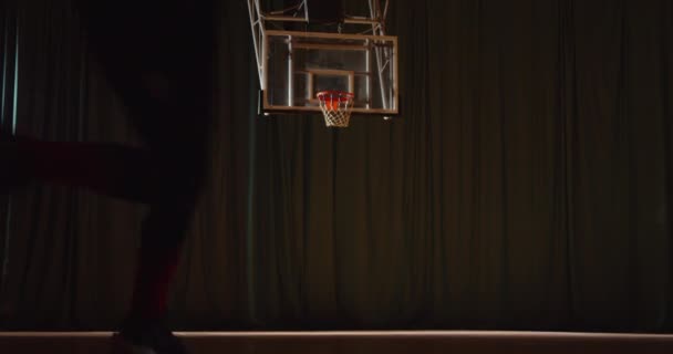Jovem caucasiano curly jogador de basquete joga a bola na cesta de treinamento noturno — Vídeo de Stock