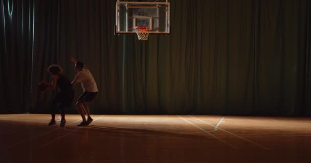 Dos jóvenes jugadores de baloncesto juegan basket ball competición enfrentamiento defensa ataque noche juego oscuridad — Vídeo de stock