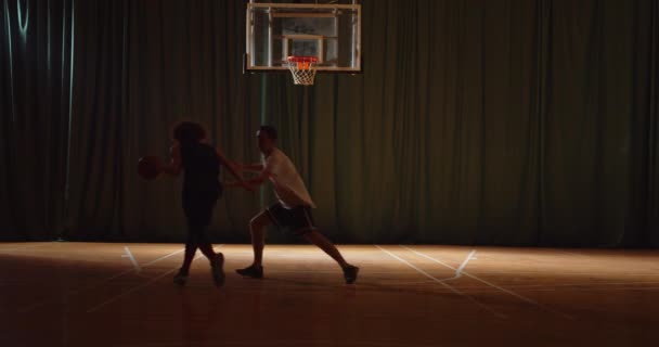 Двоє молодих баскетболістів грають в кошик м'яч змагання проти атаки нічної гри силуети темряви — стокове відео