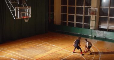 İki basketbolcunun üst görüntüsü kıvrımlı bir şekilde gece oyunu oynuyorlar. Uzak atak hücum uzak mesafe sporu.