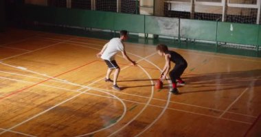 İki basketbolcunun üst görüntüsü kıvırcık, gece maçlarında top sürerken defans hücum, spor dayanıklılık salonu.