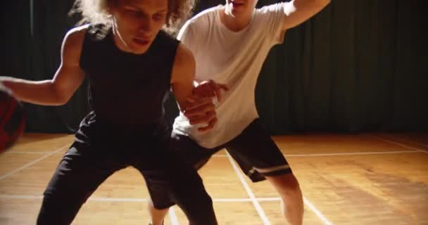 Gros plan confrontation entre deux joueurs de basket-ball endurance sportive attaque défense nuit sport salle de jeux — Video