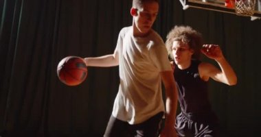 İki basketbol oyuncusu arasında yakın çekim karşılaşması. Spor dayanıklılığı hücum, savunma gecesi, spor salonu topu.
