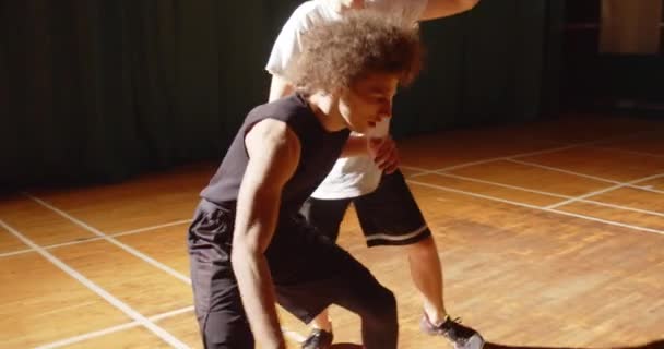 Närbild konfrontation mellan två basketspelare sport uthållighet attack försvar natt sport spel hall lockigt hår — Stockvideo
