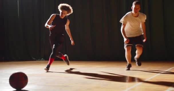 Twee jonge jongens basketbal spelers shuttle race banket hal 's avonds ray of light training uithoudingsvermogen — Stockvideo