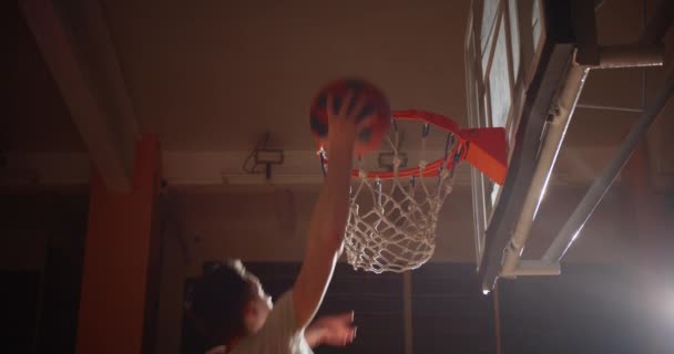 Primer plano canasta baloncesto bola Slam Dunk caucásico jugador saltar rayo de luz — Vídeos de Stock