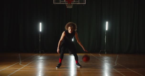 Sapık, genç, beyaz basketbolcu. Neon ışıklı arka planda top numaraları yapıyor. — Stok video