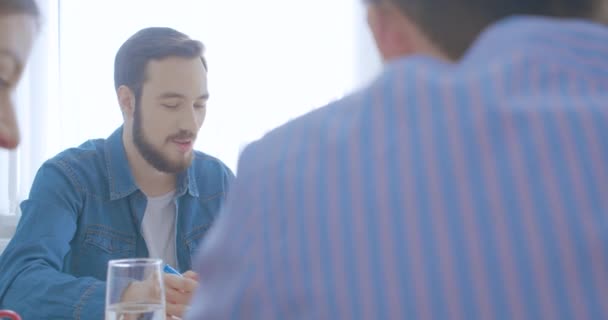 Cuatro colegas multirraciales jóvenes de la oficina trabajan discutiendo el negocio brillante del pensamiento del día — Vídeo de stock