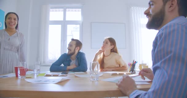 Afrikansk flicka med dreadlocks visar en presentation på kontoret fyra collegues talar skratt glädje framgång skämt — Stockvideo