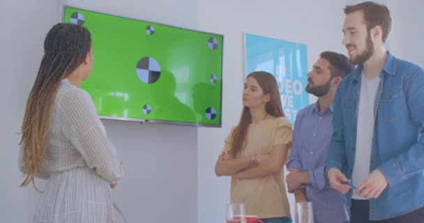 Czterech różnych współpracowników wielorasowych w dyskusji na temat prezentacji chromakey w biurze — Wideo stockowe