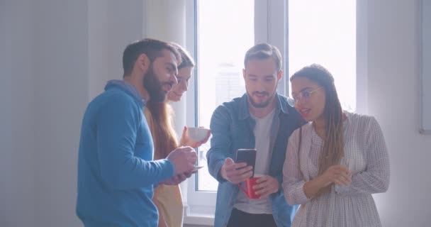 사무실에서 다양 한 인종을 가진 네 명의 동료가 커피를 마시며 대화를 나누는 스마트폰 — 비디오