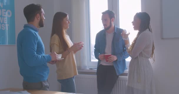 Quattro diversi colleghi multirazziali in ufficio pausa caffè conversazione conversazione discussione soleggiata stanza riposo scherzo ridere felice — Video Stock