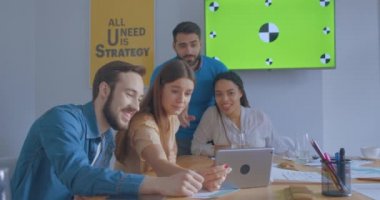 Güneşli ofisteki genç meslektaşlar tablet bilgisayar kullanıyor konferans kromatonu gülümsüyor