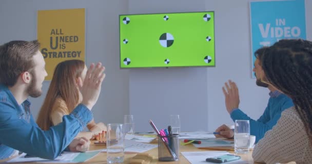 Jóvenes colegas en una oficina soleada muestran risa sonriente cromakey mirar la pantalla en línea conferencia llamada hola gesto — Vídeo de stock