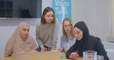 Kendine güvenen dört farklı iş arkadaşı ofis kadınları tesettür tartışma iş planı dizüstü bilgisayar grafiği kullan
