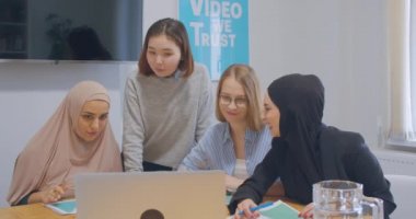 Kendine güvenen dört farklı ofis çalışanı kadın tesettür iş planı dizüstü bilgisayar kahkahaları neşesi kullan