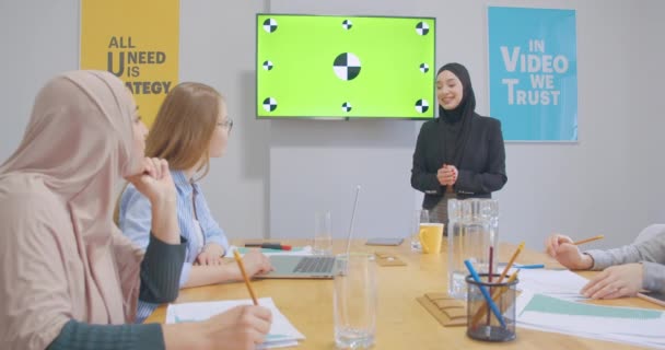 Quatre confiants divers collègues gais bureau femmes hijab discussion business plan présentation chromakey rire — Video