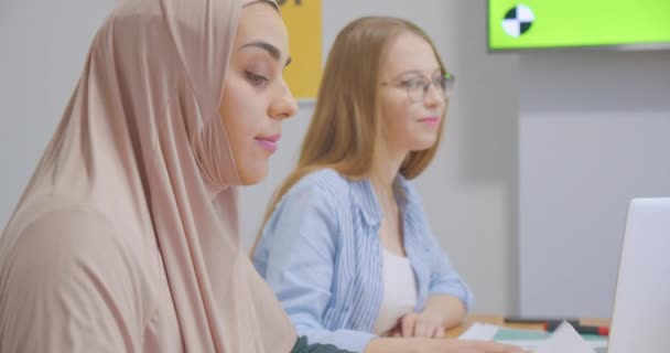 Впевнені молоді різноманітні веселі колеги офіс жінки хіджаб обговорення бізнес-план презентації хроматичних ноутбуків обговорення — стокове відео