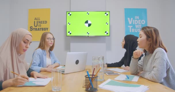 Cuatro jóvenes confiados diversos colegas alegres oficina mujeres hijab discusión plan de negocios presentación cromakey éxito juvenil — Vídeo de stock