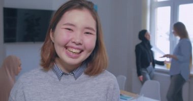 Arka planda gülümseyen mutlu, pozitif Asyalı ofis kızı portresi
