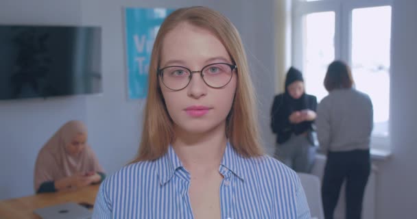 Retrato de una joven hermosa rubia caucásica gafas fondo de oficina — Vídeo de stock