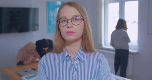 Porträtt av en ung vacker säker stolt vit blond glasögon kontor bakgrund — Stockvideo
