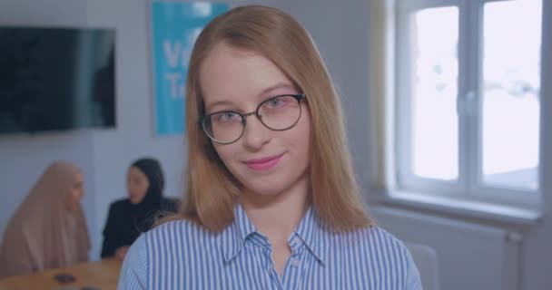 Porträt junge schöne Lächeln schlaue kaukasische Blondine Brille Büro Hintergrund — Stockvideo