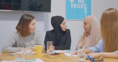 Kendine güvenen dört farklı bayan meslektaşın genç ofis çizelgeleri iş gülüşü planlıyor