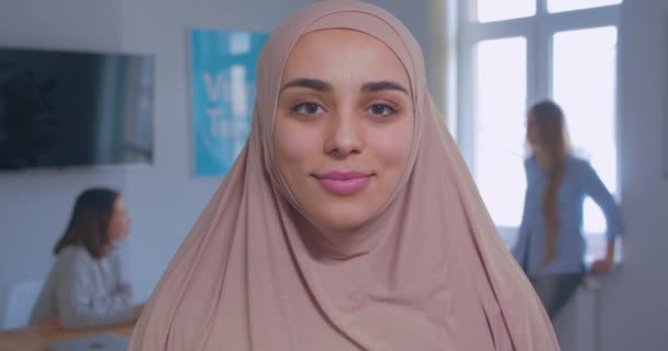 Gros plan portrait d'une jeune belle musulmane confiante et souriante en fond de bureau hijab — Video