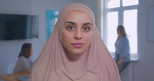Close-up portrait of a young beautiful serious muslim girl in hijab office background — Stock Video