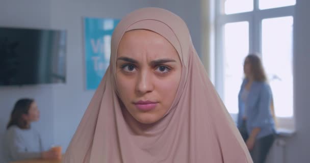 Nahaufnahme Porträt einer jungen schönen ernsten wütenden muslimischen Mädchen im Hijab-Büro Hintergrund — Stockvideo