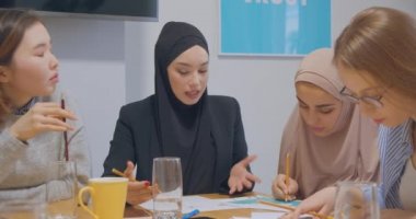 Kendine güvenen dört farklı kadın meslektaşı genç ofis grafikleri iş fikri planlıyorlar. Başarı tesettüre girdi.