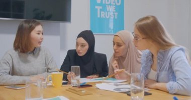 Kendine güvenen dört farklı kadın meslektaşı genç ofis çizelgeleri iş fikri planlıyorlar..
