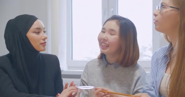 Három irodai kommunikációs szünet kollégák használ egy smartphone változatos multiraces boldog vicc hidzsáb ázsiai — Stock videók