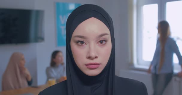 Close-up portrait of a young beautiful confident Caucasian girl in hijab office background — Stock Video