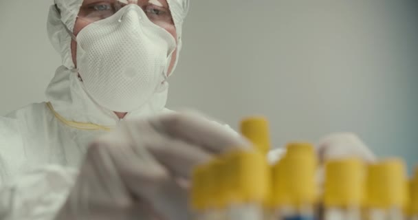 Close-up laboratorio científico asistente guantes tubos de ensayo pipeta virus reactivos vacuna investigación respirador máscara comparación — Vídeo de stock