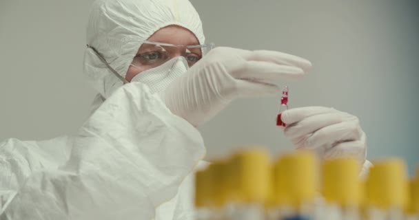 Close-up laboratorio científico asistente guantes tubos de ensayo pipeta virus ampolla reactivos rojos vacuna investigación respirador máscara — Vídeos de Stock