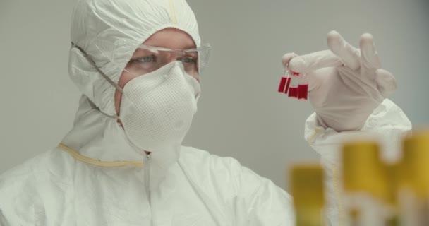 Close-up laboratorio científico asistente guantes tubos de ensayo pipeta virus ampolla rojo reactivos vacuna investigación respirador máscara comparación — Vídeo de stock