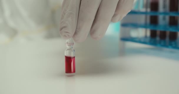 Close-up laboratorio científico asistente guantes tubos de ensayo pipeta virus ampolla reactivos rojos vacuna fondo blanco — Vídeos de Stock