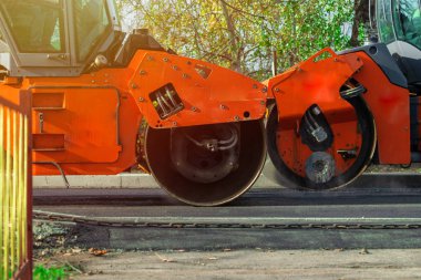 Yol silindirleri yeni asfalt yolu inşa ediyor. Vagon, kamyon, yürüyüş makinesi.