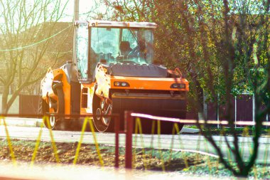 Yol silindirleri yeni asfalt yolu inşa ediyor. Vagon, kamyon, yürüyüş makinesi.