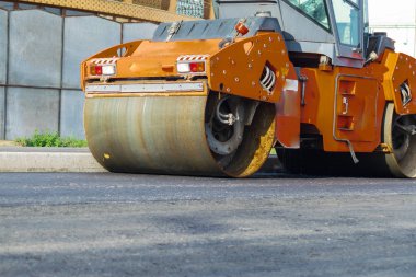 Yol silindirleri yeni asfalt yolu inşa ediyor. Vagon, kamyon, yürüyüş makinesi.