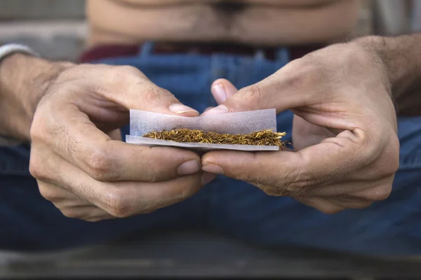 Manos de hombre enrollando un porro — Foto de Stock