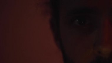 Close up portrait of the look of a man illuminated by colored lights in the dark