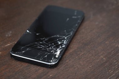 ahşap masa üzerinde kırık dokunmatik ekranlı akıllı telefon