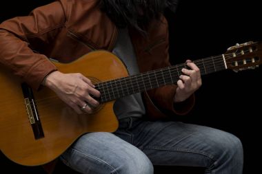 Uzun saçlı erkek gitarist deri akustik gitar ile oynarken