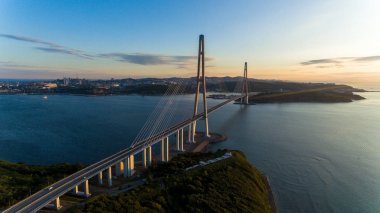 Amazing zooming out aerial view of the Russky Bridge, the world's longest cable-stayed bridge, and the Russky (Russian) Island in Peter the Great Gulf in the Sea of Japan. Sunrise. Vladivostok, Russia clipart