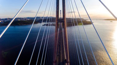 Amazing zooming out aerial view of the Russky Bridge, the world's longest cable-stayed bridge, and the Russky (Russian) Island in Peter the Great Gulf in the Sea of Japan. Sunrise. Vladivostok, Russia clipart