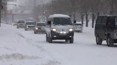 Arabalar bir kar yağışı sırasında git karla kaplı şehir, şehir Vladivostok, ağır çekim çekim